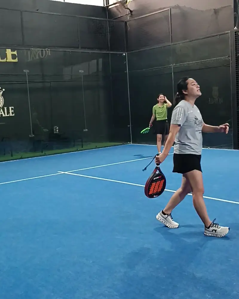A player on the blue padel court at The Royale Padel